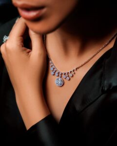 Close-up of a woman wearing an elegant diamond necklace against a black silk fabric.